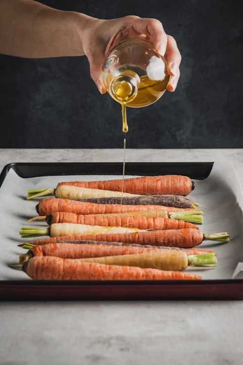 pouring olive oil on carrots